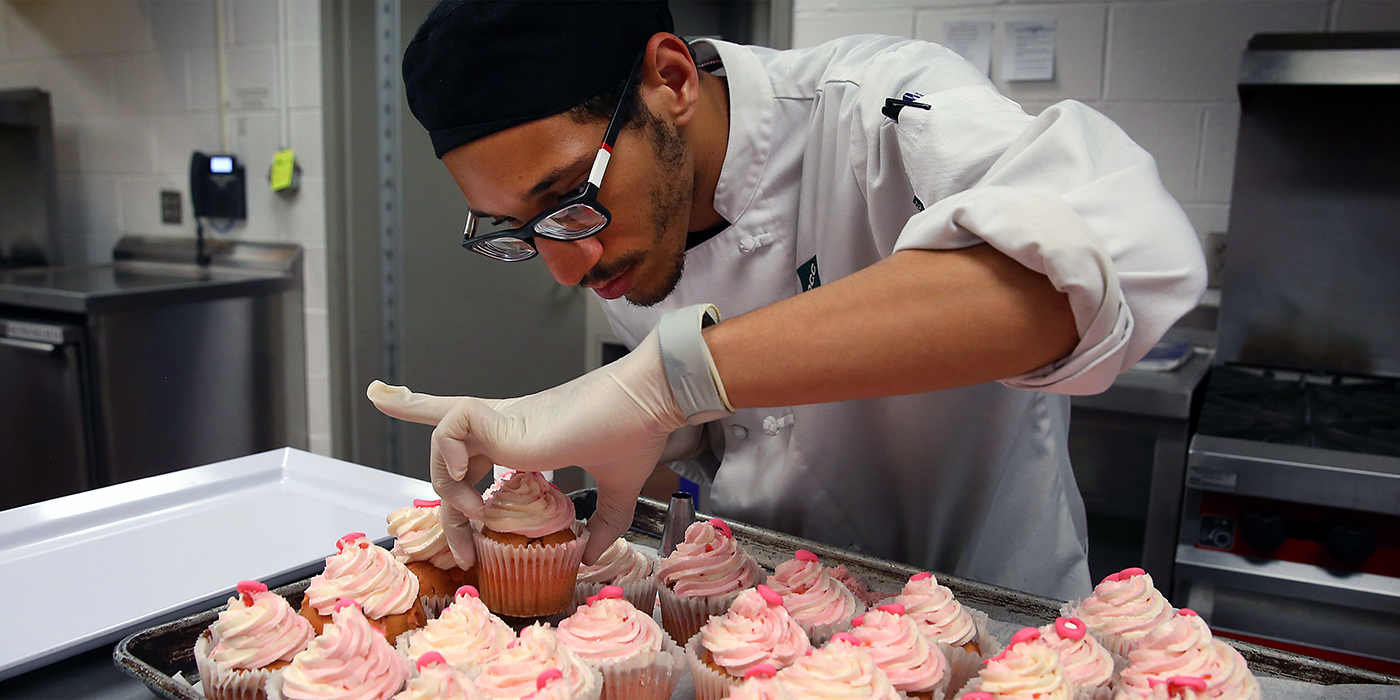 A Central Piedmont baking student placing cupcakes on a platter