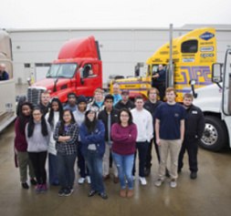 group of students in front of semi trucks