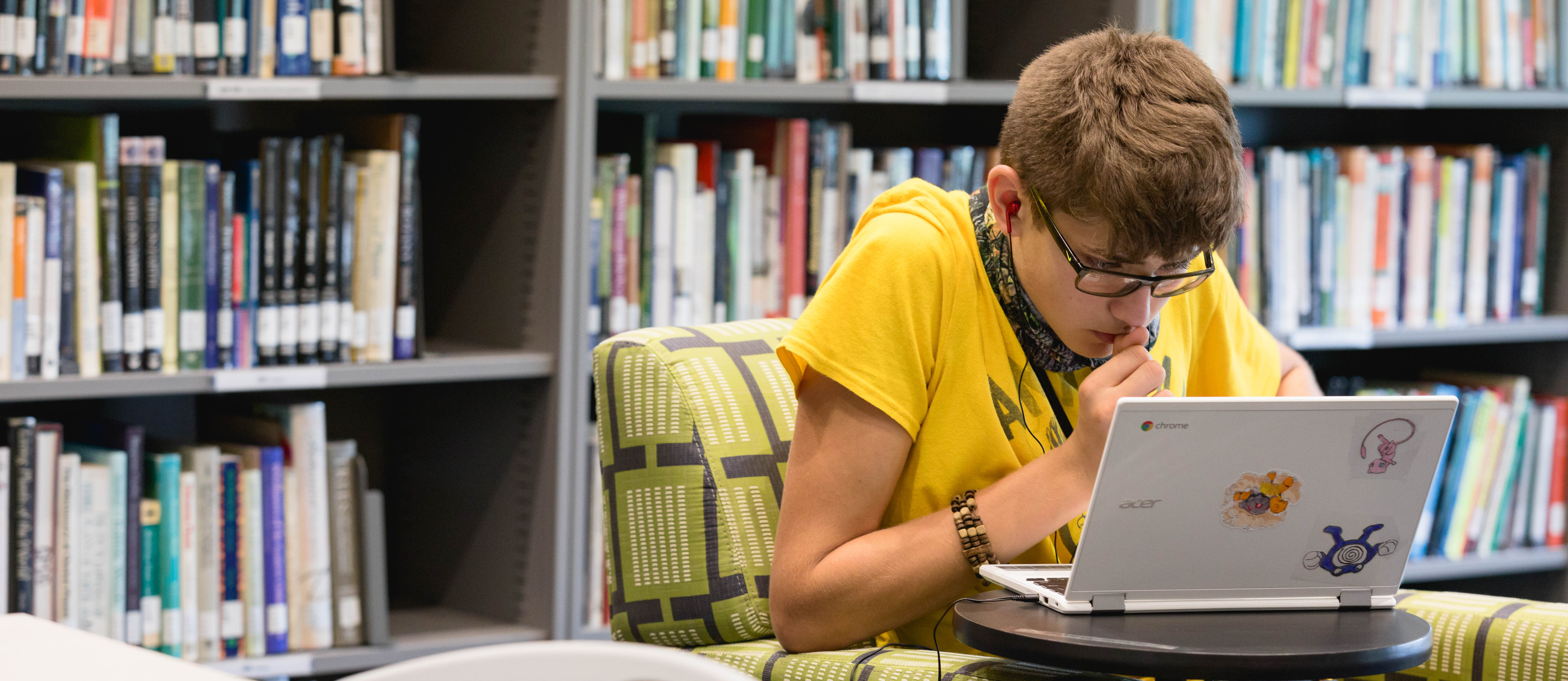 Library Student in front of Laptop and Bookshelves