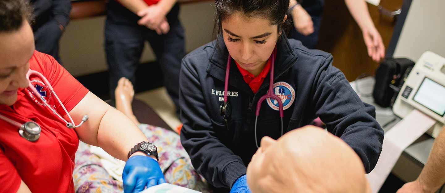 Students practicing getting vital signs from a medical dummy