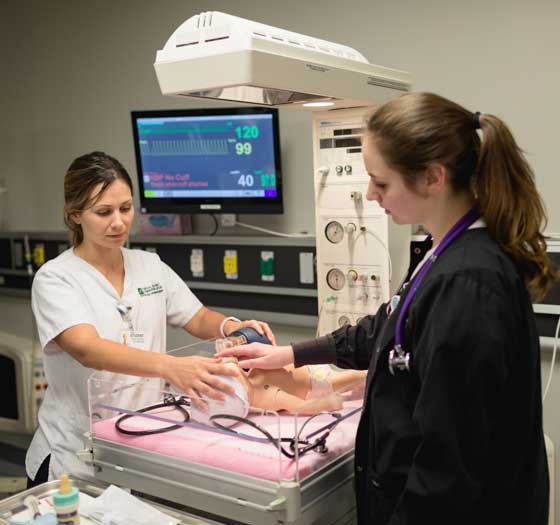 Nurse aide performing manual breathing on infant