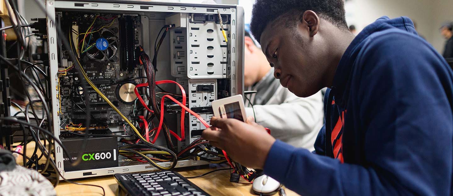 Student working on the internals of a desktop computer