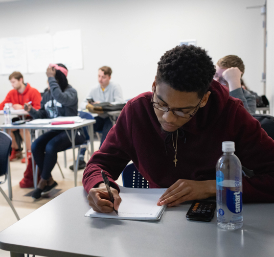 student with calculator taking notes in class