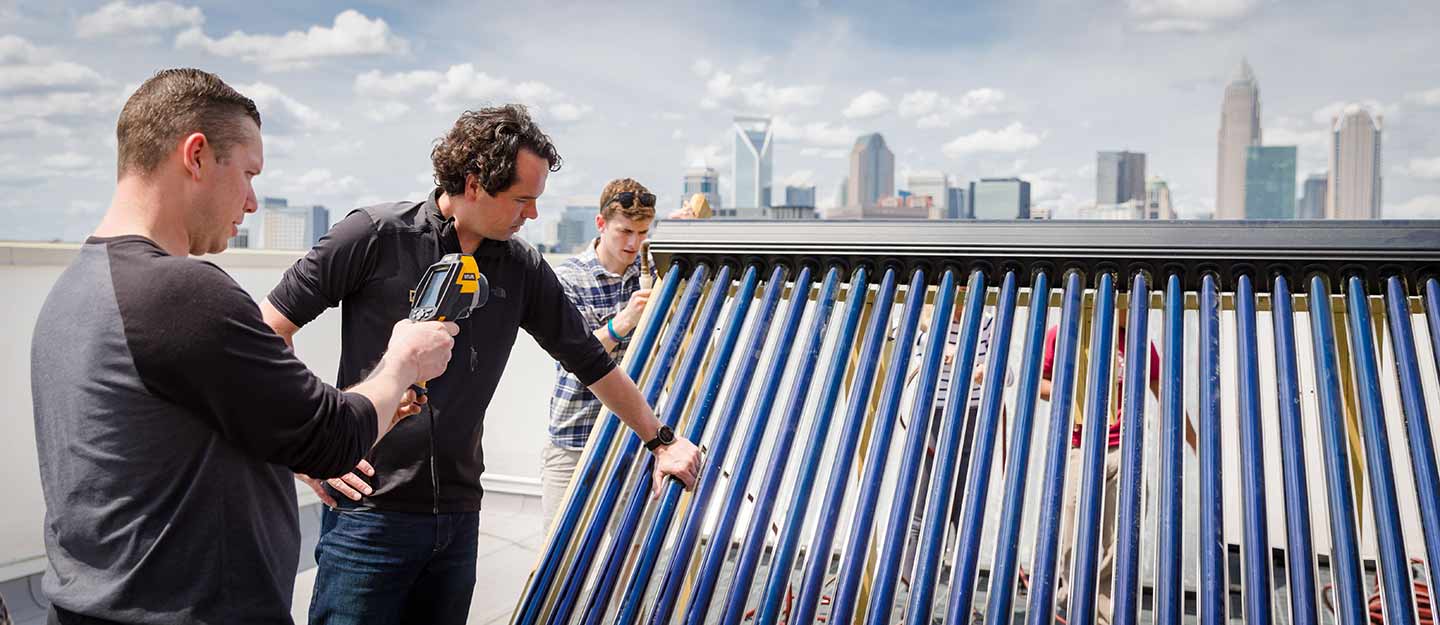 three students installing a sustainable solution on a roof