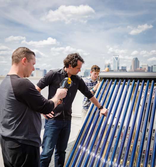 three students installing a sustainable solution on a roof