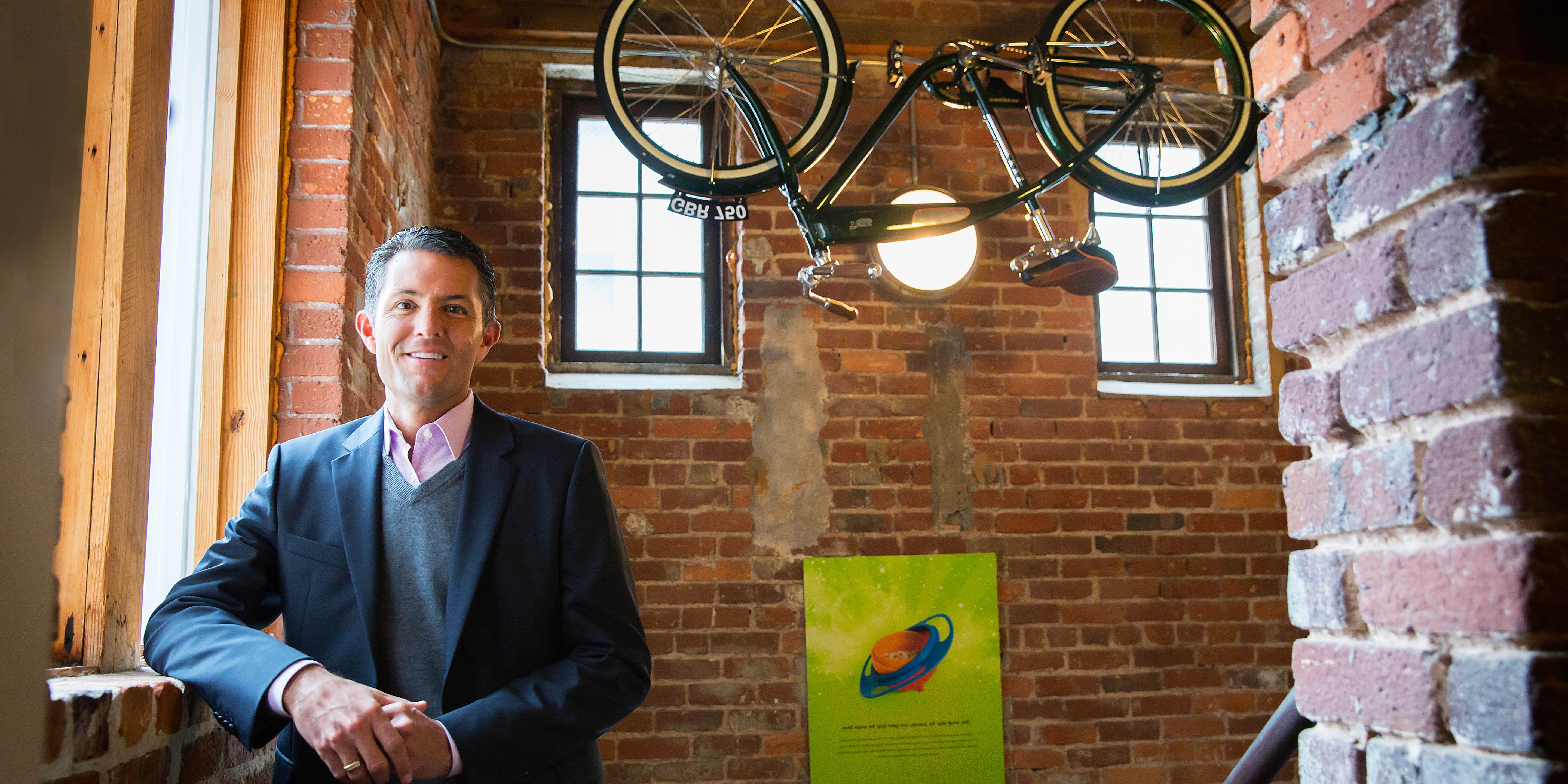 Continuing Education student Louis Foreman smiling in brick room with bicycle hanging from ceiling