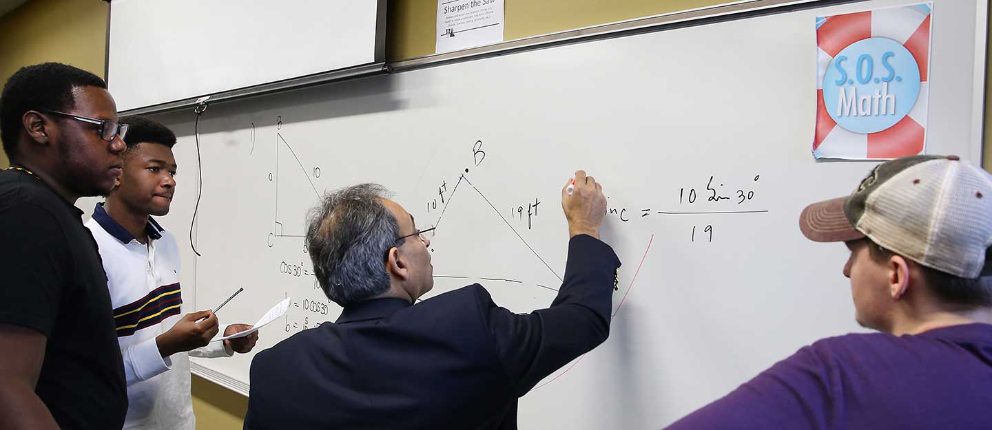 Instructor explaining a math problem to students on a whiteboard