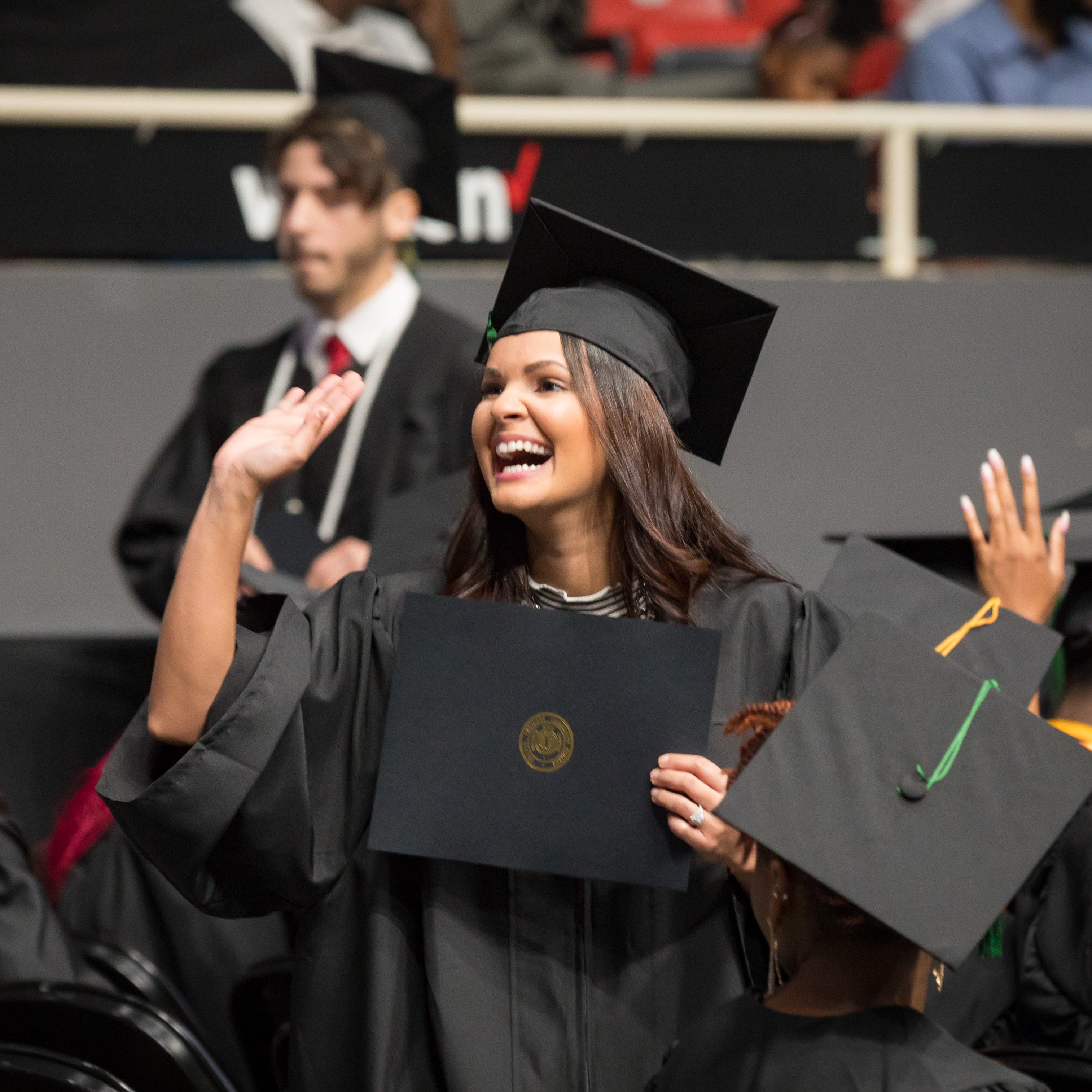 student happily waving at graduation