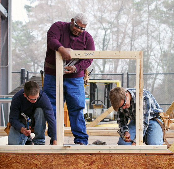 three students building the frame of a structure