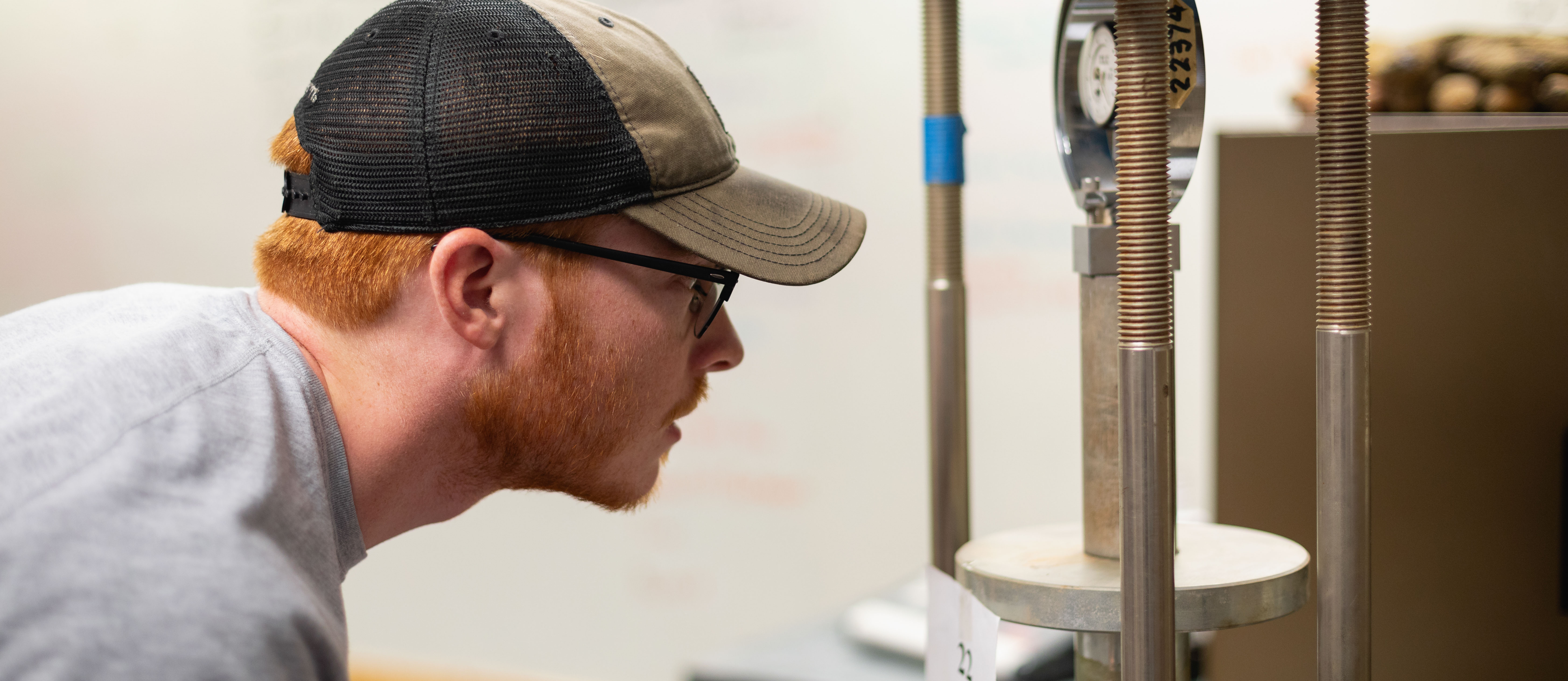 civil engineering student wearing hat examining some pipes and a meter