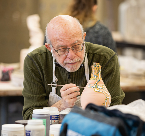 adult learner in ceramics course painting pottery