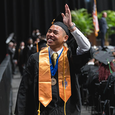 student waving at graduation