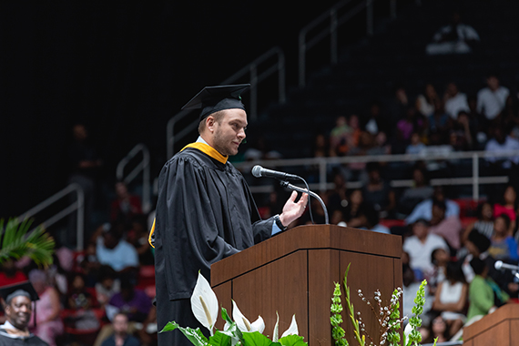 Alumni Speaking from podium at graduation