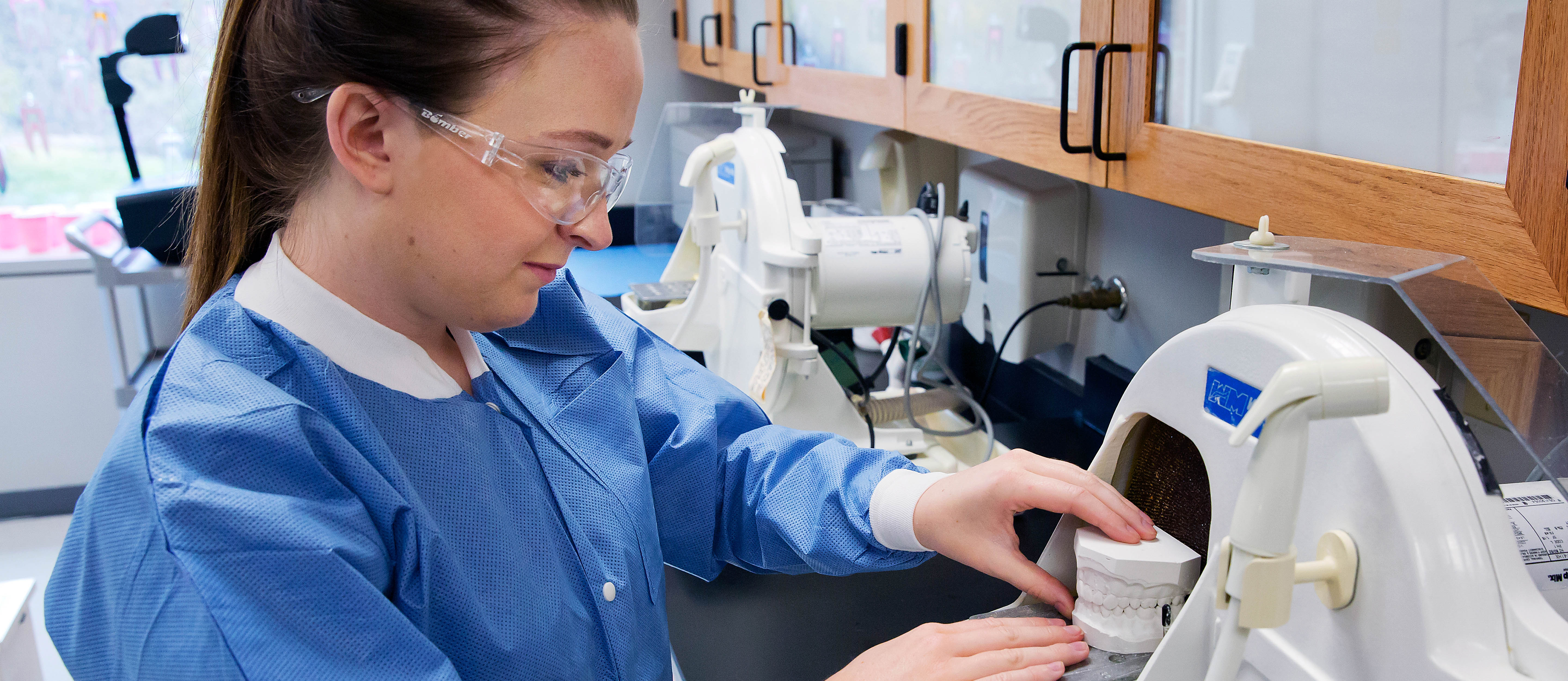 dental assisting student with dental mold in machine