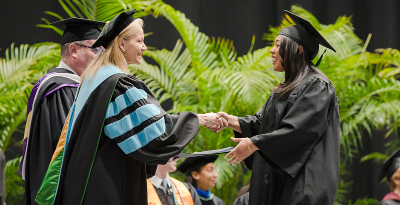 Dr. D shaking hands with graduate on graduation stage