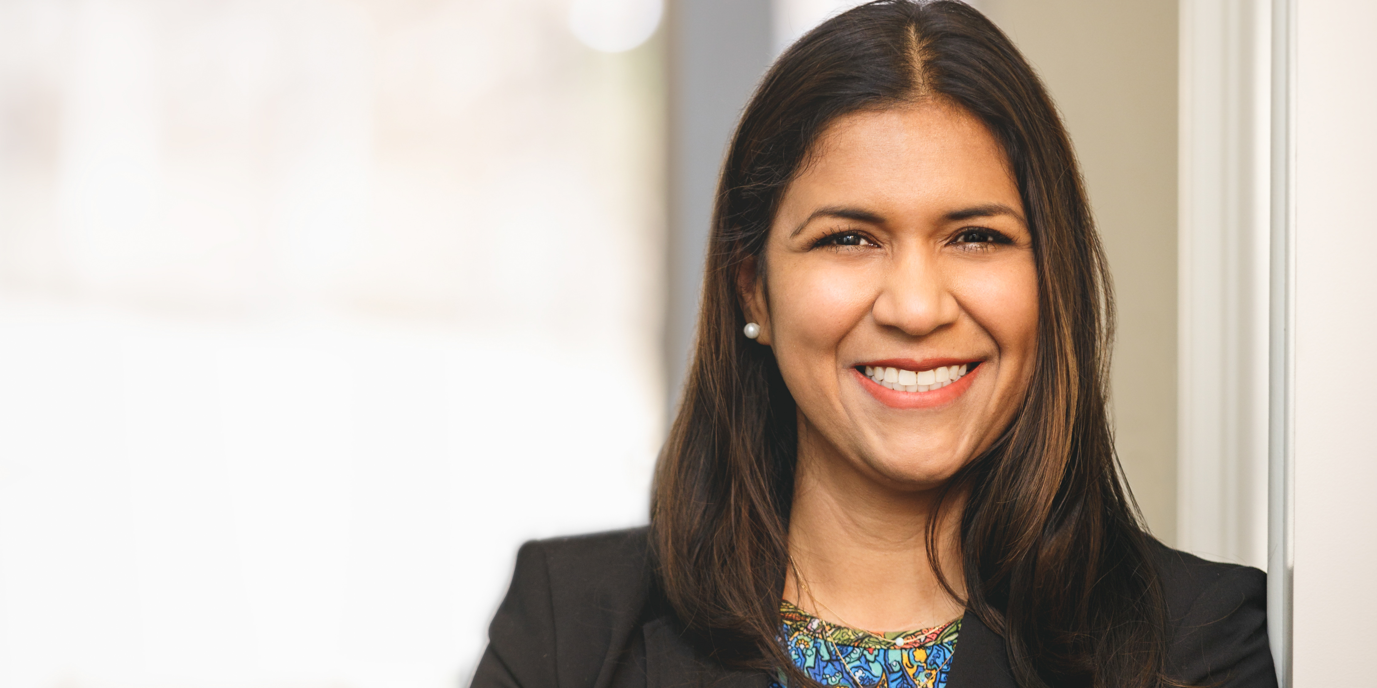 professional Isabel Salas leaning against wall and smiling at camera