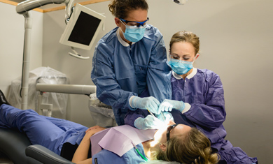 dental hygienist and dental assistant working together with patient