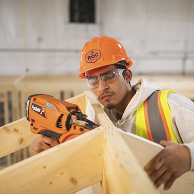 man working with drill on construction site, wearing hard hat with the ROC logo