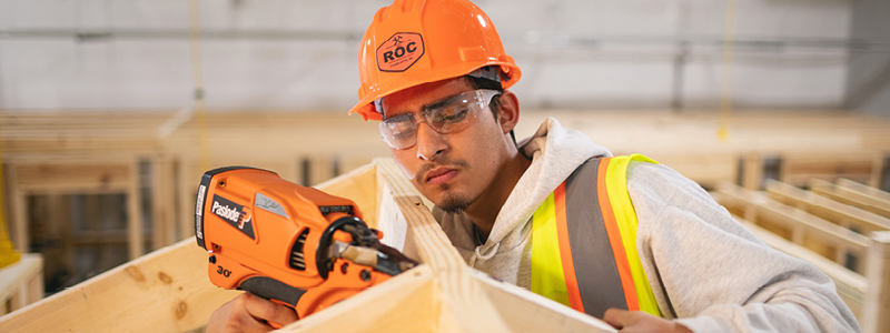 man working with drill on construction site, wearing hard hat with the ROC logo