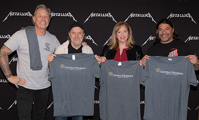 Rock band Metallica holding Central Piedmont tees with Kathy Rummage