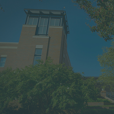 looking up at tower on Harper Campus with trees