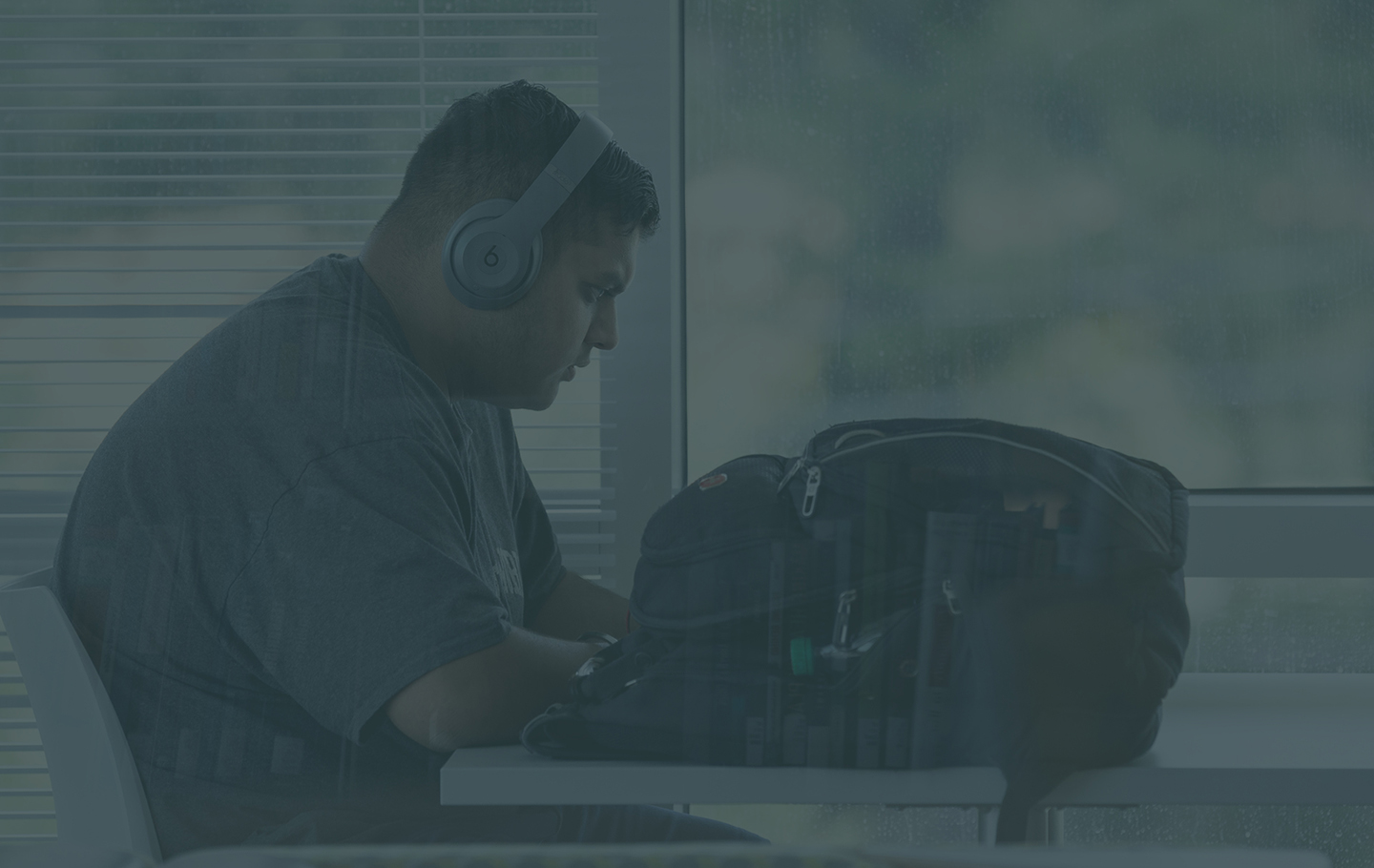 male student working at a desk with headphones on