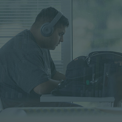 male student working at a desk with headphones on