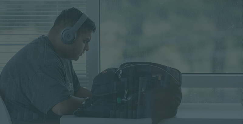 male student working at a desk with headphones on