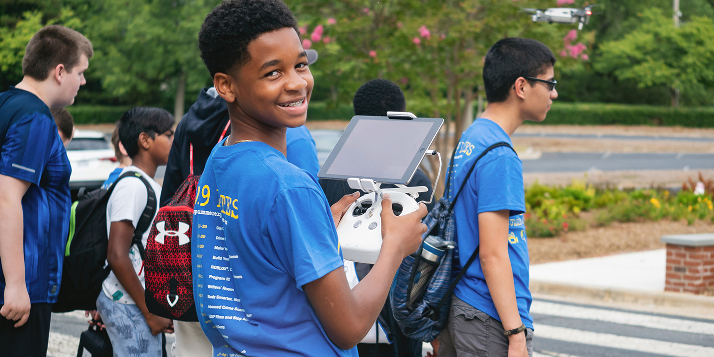 summer camp student with drone outside on campus