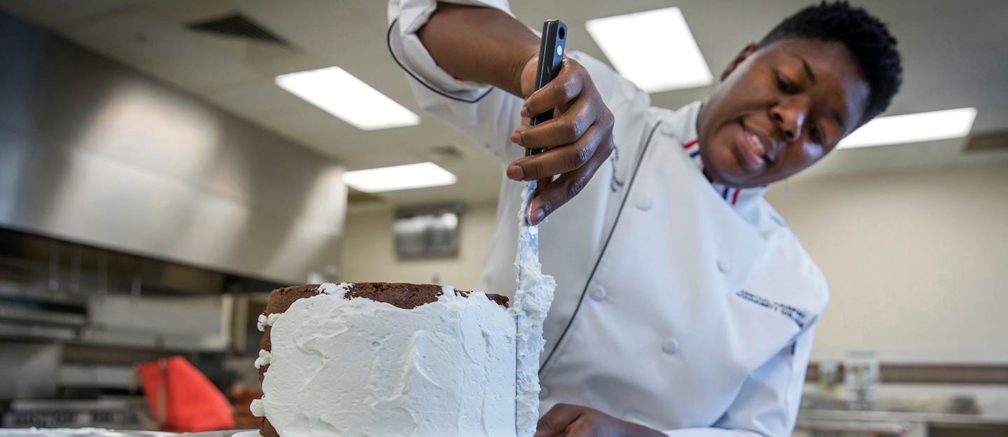 Corporate and Continuing Education hospitality student icing a cake