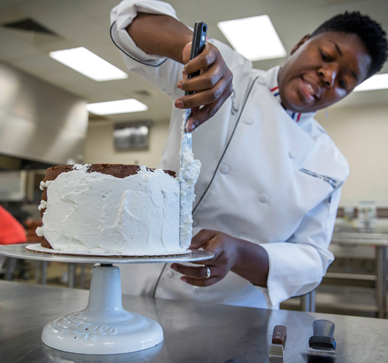Continuing Education hospitality student icing a cake