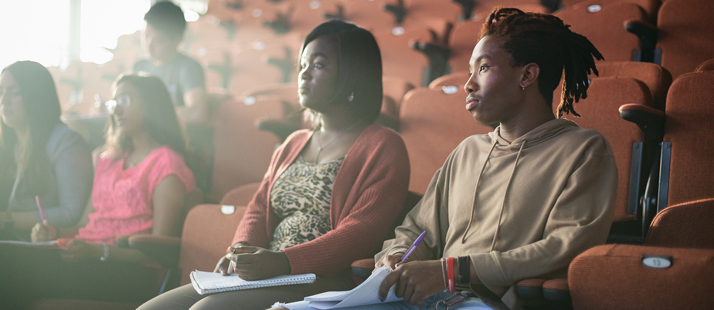 two students sitting in an auditorium classroom listening to their teacher