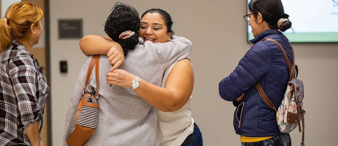 two students hugging and smiling at an event