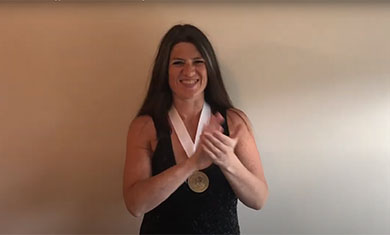 Phi Theta Kappa officer wearing medal smiling and applauding spring 2020 inductees