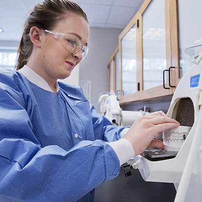 dental assisting student with dental mold in machine