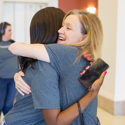 President Dr. Deitemeyer hugging a staff member at a staff event