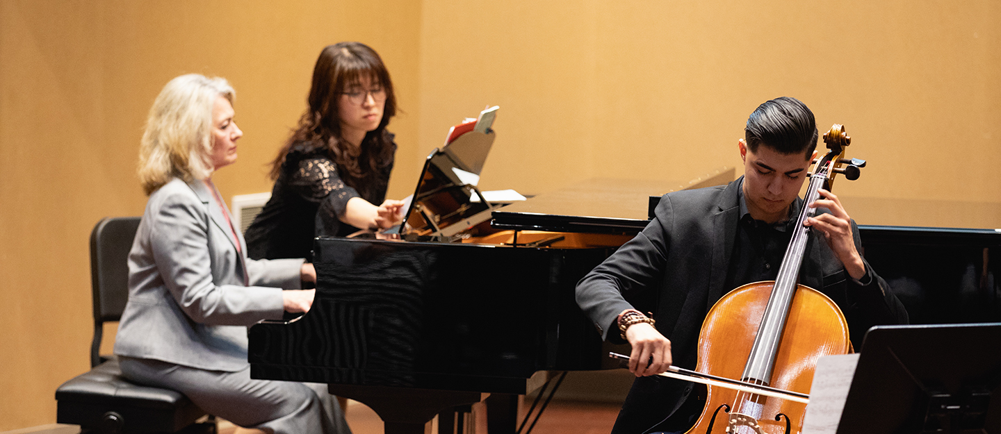 a cellist at his recital accompanied by two pianists at piano