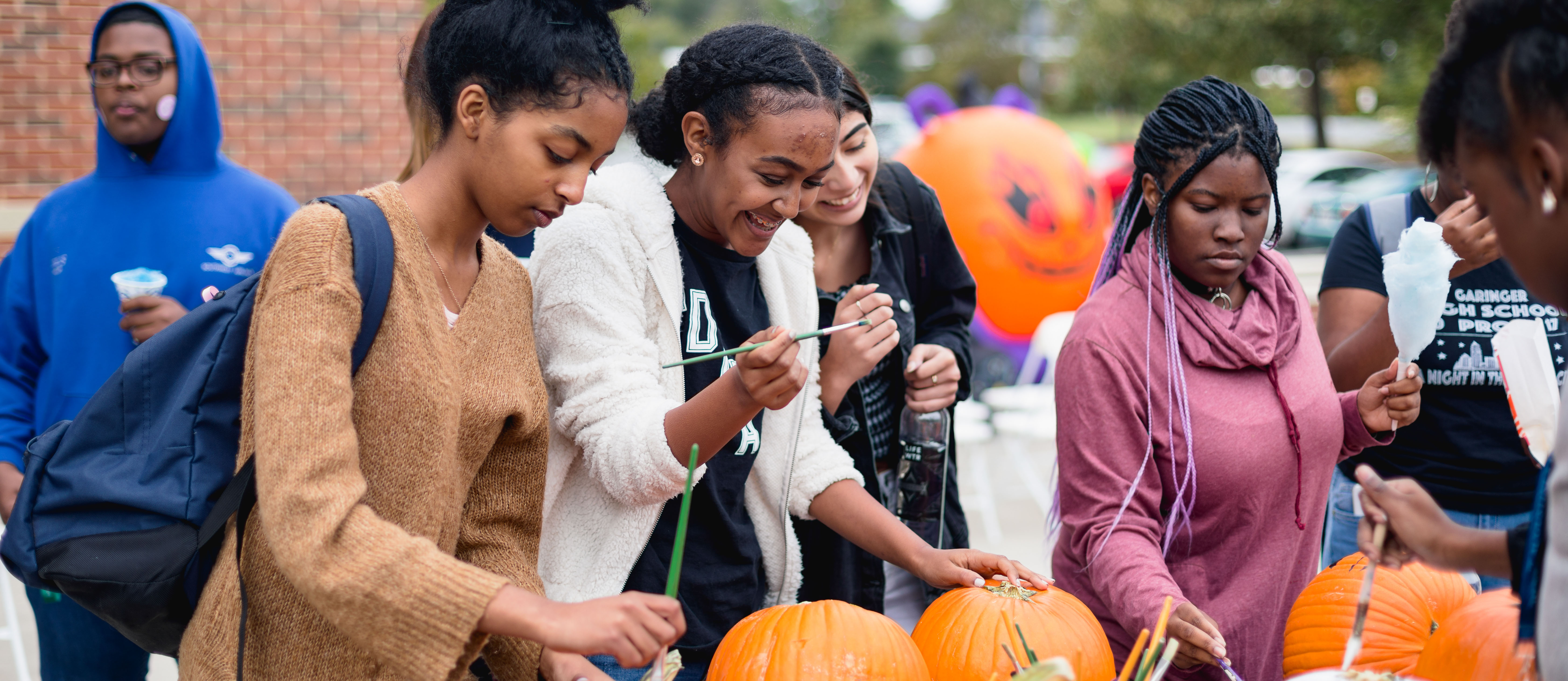students picking pumpkins to paint at an outdoor student event