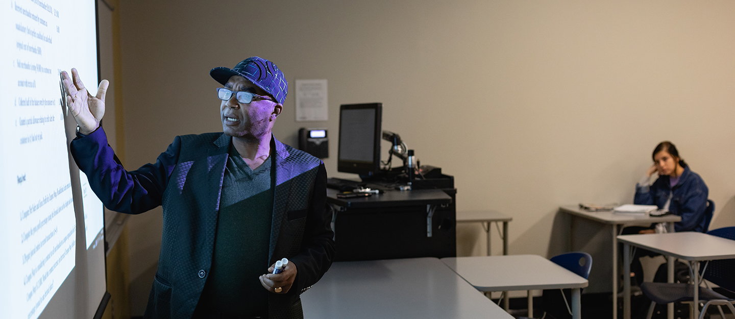 an instructor at the the board teaching off a projector screen