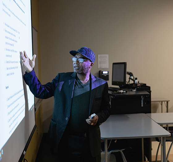 an instructor at the the board teaching off a projector screen