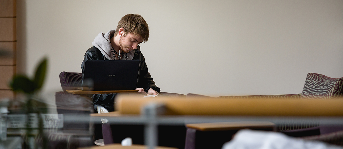 student at Levine Campus working in a chair in a lobby