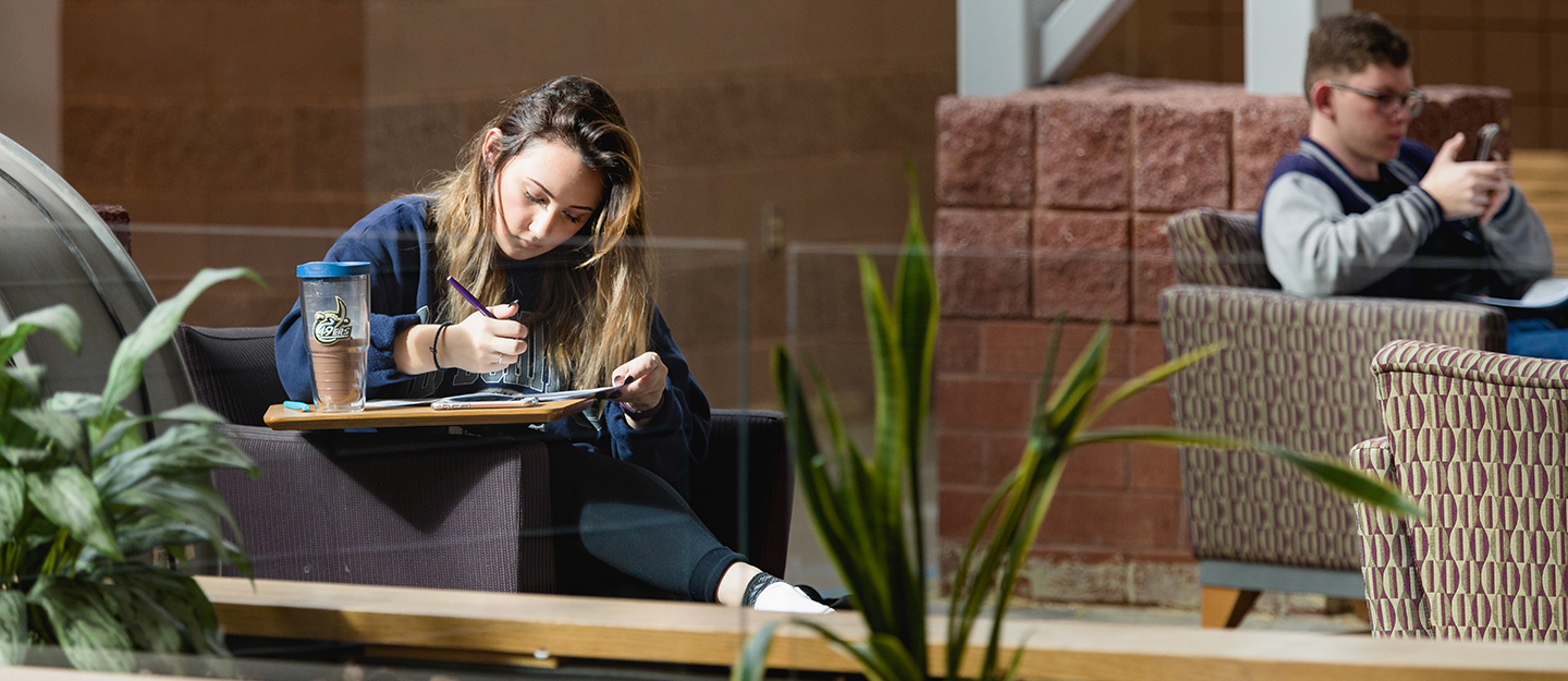 student at Levine Campus working in a chair in a lobby