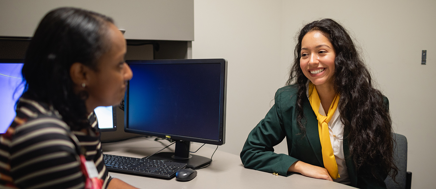 an advisor giving a student career advice at a desk in an office