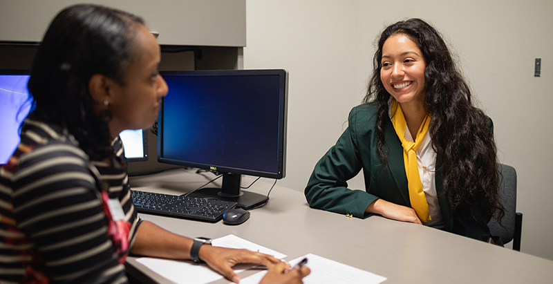 an advisor giving a student career advice at a desk in an office