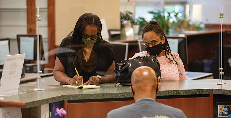 a student and their mother, wearing masks, filling out paperwork at a Central Piedmont service desk