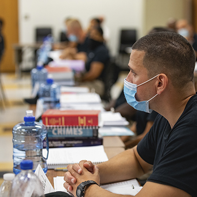 student wearing mask listening in class with stack of textbooks