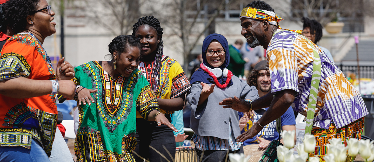 students dancing at spring festival in traditional African dress with drummer