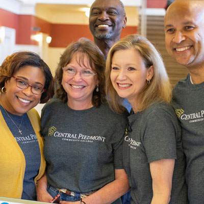 Central Piedmont president Dr. Deitemeyer and employees in group photo with cardboard Instagram post frame