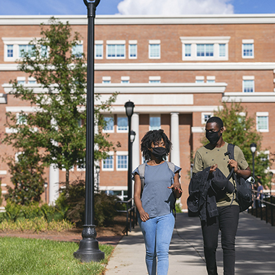 two students wearing masks chatting while walking on Central Campus