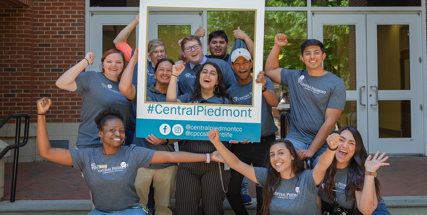 Central Piedmont employees and students in group photo with social media frame